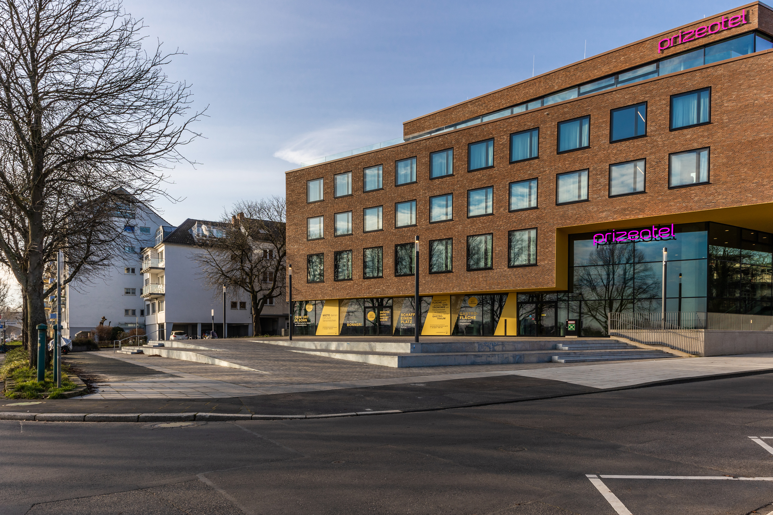 Die braune Außenfassade und der Parkplatz des prizeotels in Bonn-City
